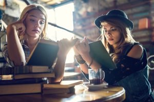 Young women relaxing in a library while studying from books.